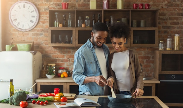 Couple Noir Aimant Préparer Un Repas Avec Une Recette Ensemble Dans Une Cuisine Moderne. Légumes Frits En Famille