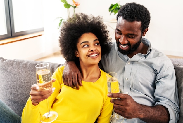 Couple noir buvant du vin mousseux à la maison pour célébrer - Un couple joyeux se lie et prend l'apéritif