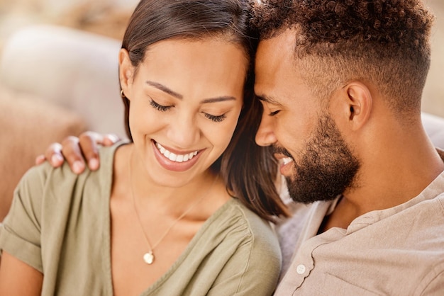 Couple noir heureux et amour sur le canapé dans le salon en gros plan et câlin pour les soins de liaison et ensemble Femme homme et bonheur pour embrasser le sourire et romantique pour les relations dans la maison ou le salon