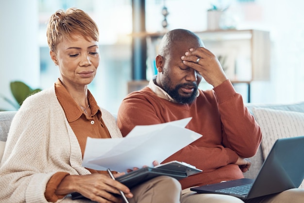 Couple noir stress et ordinateur portable dans les dépenses de la dette financière ou les factures hypothécaires ensemble sur le canapé du salon à la maison Homme et femme souffrant de paiements de pression financière ou de problèmes sur ordinateur