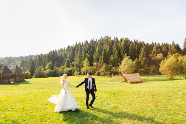 Couple nouvellement marié marchant sur la pelouse dans les montagnes