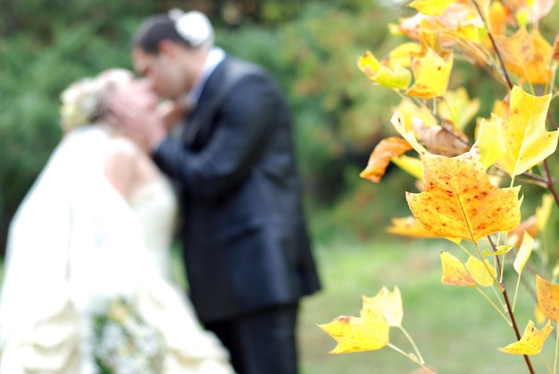 Photo le couple nouvellement marié s'embrassant dans le parc automnal