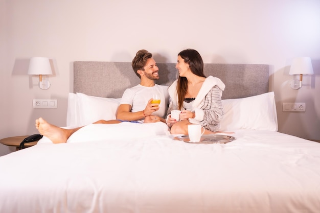 Un couple nouvellement réveillé en pyjama prenant du café et du jus d'orange pour le petit-déjeuner