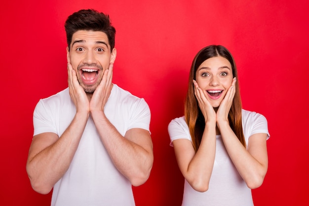 Couple occasionnel posant contre le mur rouge