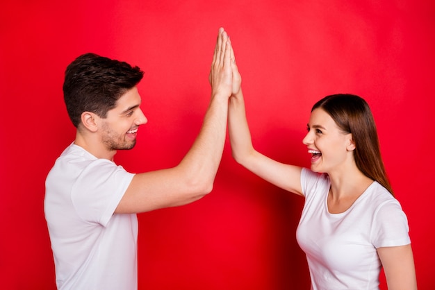 Couple occasionnel posant contre le mur rouge