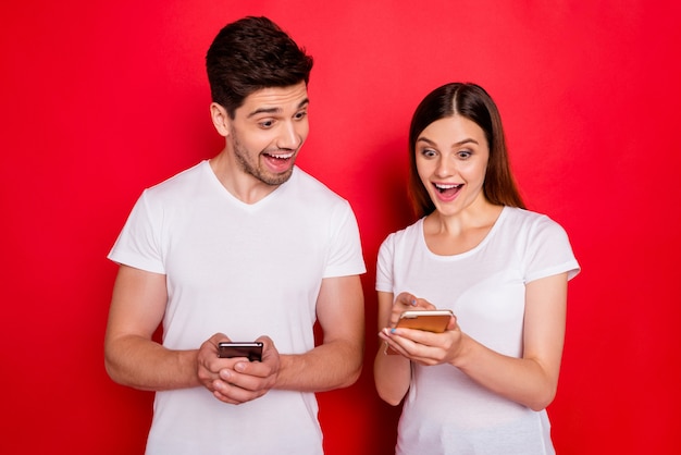 Couple occasionnel posant contre le mur rouge