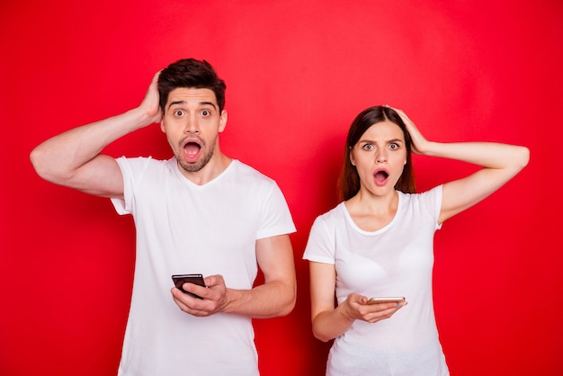 Couple occasionnel posant contre le mur rouge