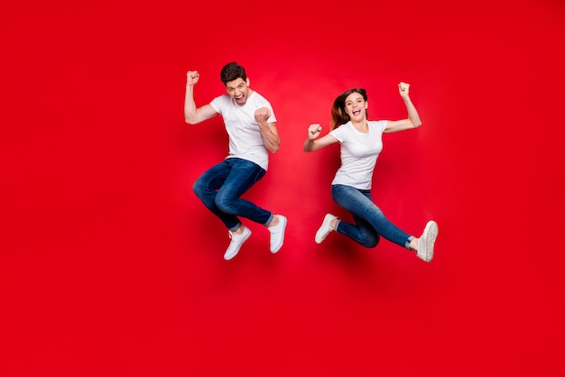 Couple occasionnel posant contre le mur rouge