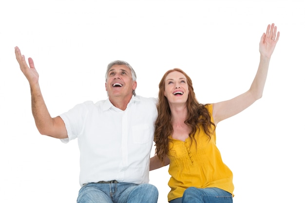 Couple occasionnel souriant avec les bras levés