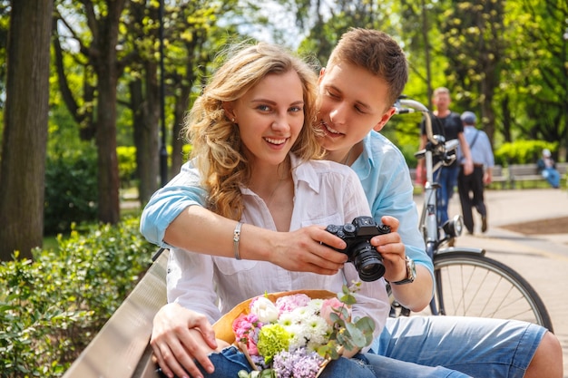 Couple occasionnel utilisant un appareil photo reflex numérique compact dans un parc d'été.