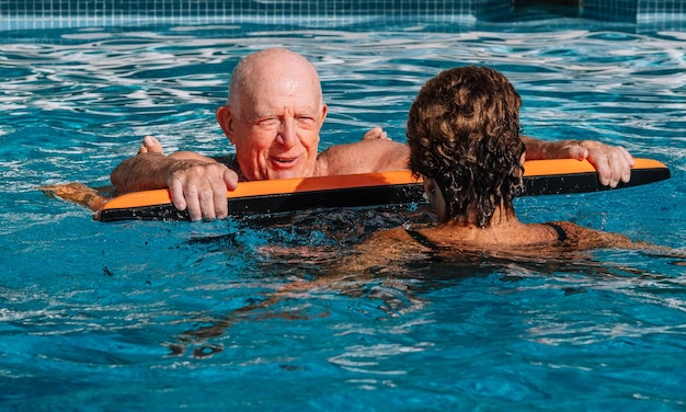 Un couple d'octogénaires avec une très belle apparence physique ils profitent de la piscine l'été Situation décontractée