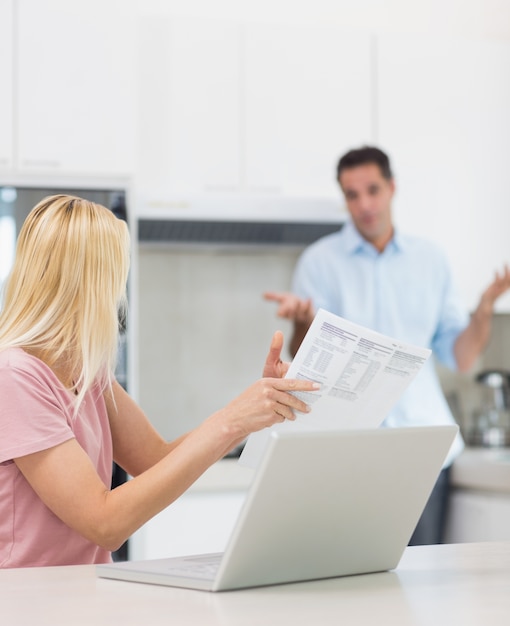 Couple avec ordinateur portable et facture dans la cuisine