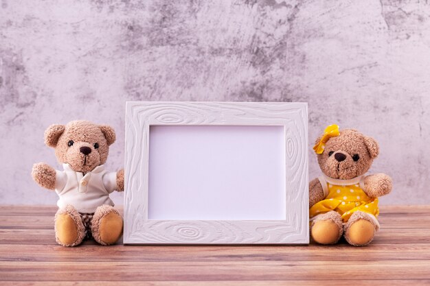 Couple ours en peluche avec cadre photo sur table en bois.