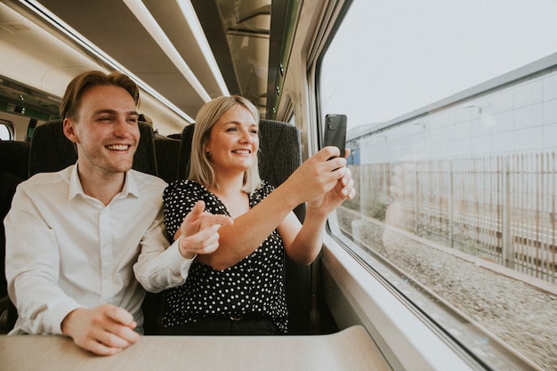 Couple par la fenêtre du train prenant une photo du paysage