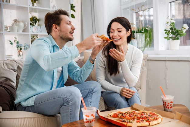 Couple partageant une pizza et mangeant