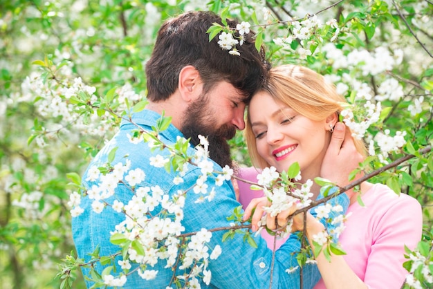 Un couple passe du temps au printemps arbre en fleurs couple de jardin rire et étreindre joyeux jour de pâques