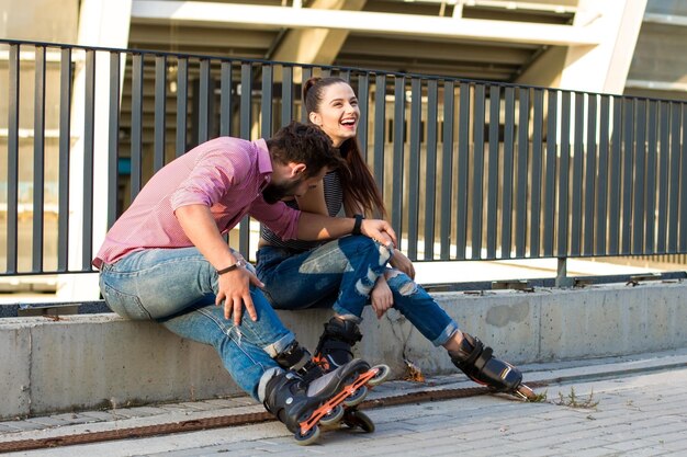 Couple sur patins à roues alignées est assis.