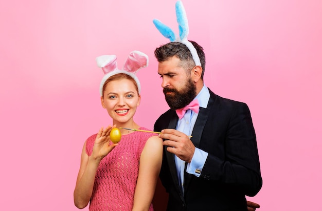 Couple peignant des oeufs pour la famille de lapin de pâques célébrer les oreilles de lapin de joyeuses fêtes de pâques