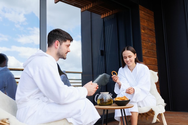 Couple en peignoirs buvant du thé avec des bagels après des traitements de spa