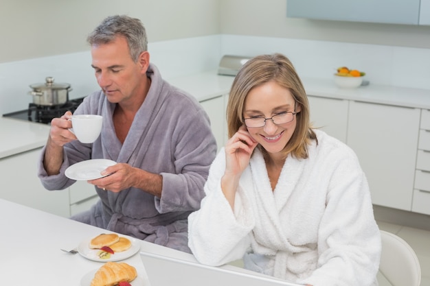 Couple en peignoirs prenant son petit déjeuner dans la cuisine