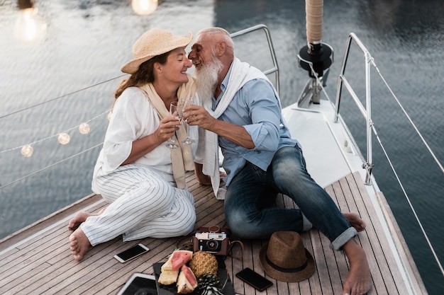 Couple de personnes âgées acclamant avec champagne sur voilier pendant les vacances d'été - Focus sur le visage de l'homme