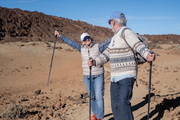 Un couple de personnes âgées actives et insouciantes avec un sac à dos se promènent à l'extérieur à l'aide de poteaux en profitant de la nature