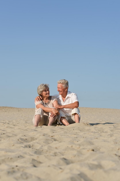 Couple de personnes âgées aimant se reposer sur le sable en été