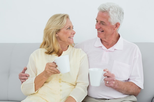 Couple de personnes âgées aimant avec des tasses de café à la maison