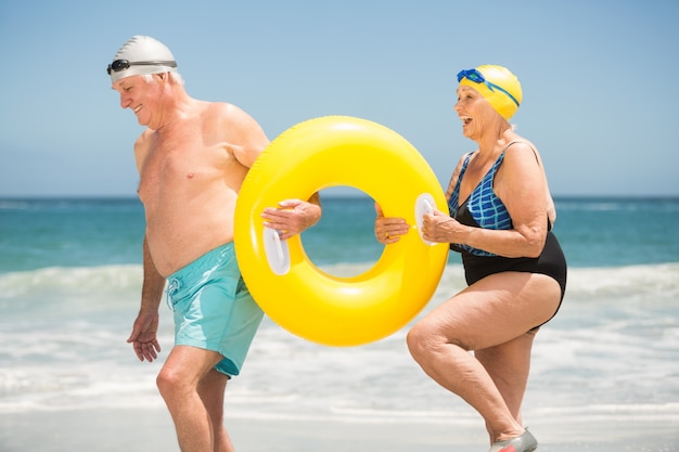 Couple de personnes âgées avec anneau de natation à la plage