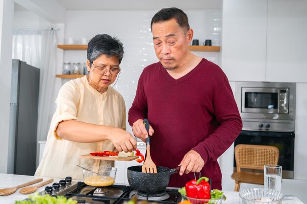 Couple de personnes âgées asiatiques cuisinant dans la cuisine pour préparer le dîner