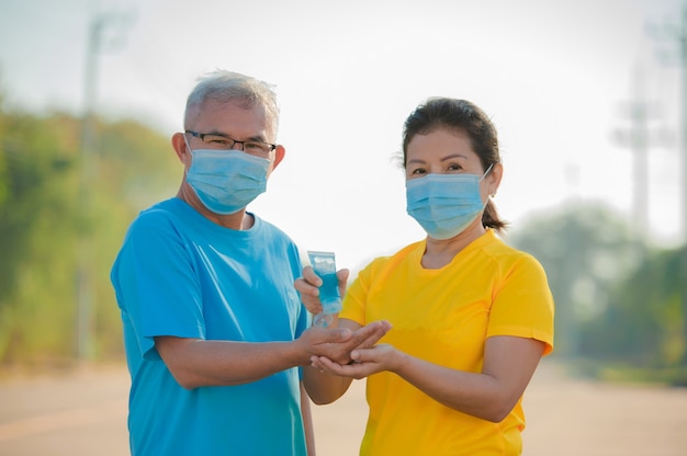 Un couple de personnes âgées asiatiques porte un masque facial utilise un gel d'alcool pour le nettoyage des mains protège le coronavirus Covid 19, senior homme femme vieille assurance