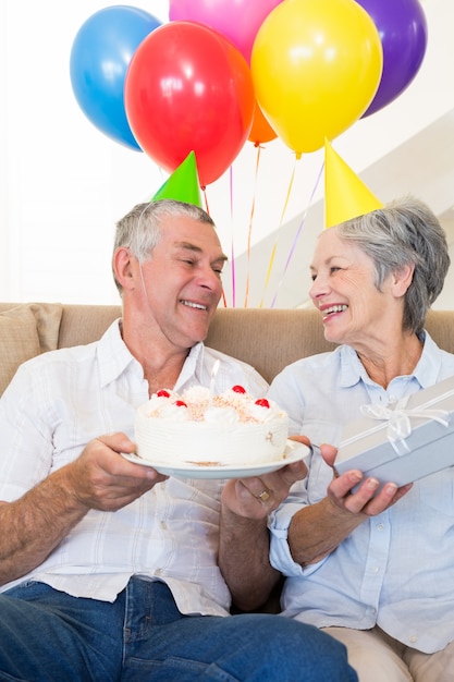 Couple de personnes âgées assis sur un canapé célébrant un anniversaire