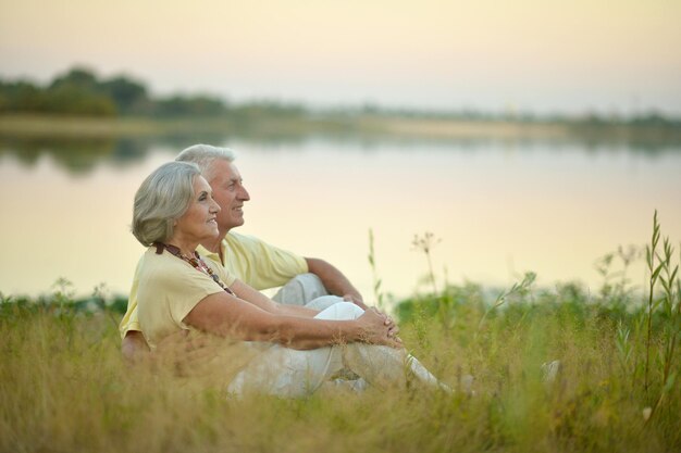 Couple de personnes âgées assis sur l'herbe