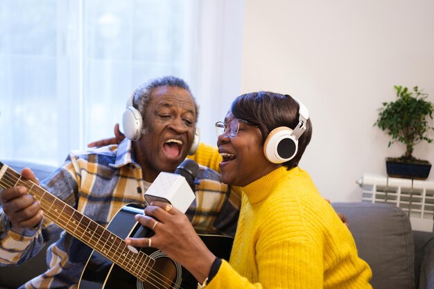 Couple de personnes âgées chantant karaoké ensemble dans leur salon s'amusant avec des jeux vidéo de musique Concept fun retraités