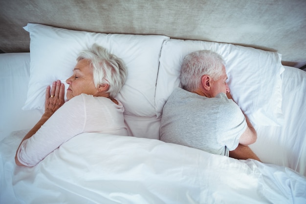 Couple de personnes âgées dormir sur le lit