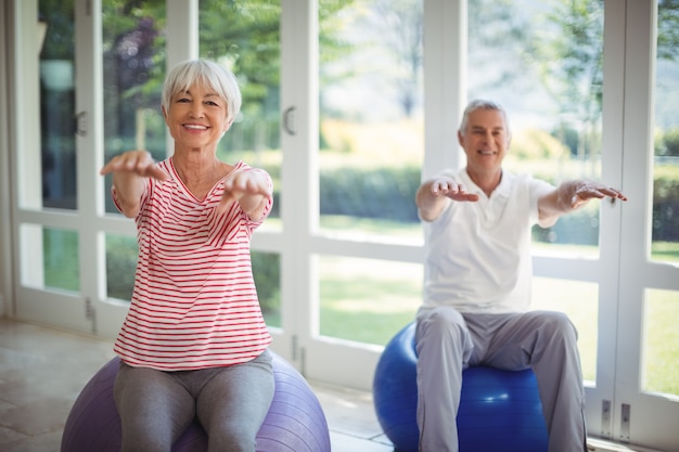 Couple de personnes âgées effectuant des exercices d'étirement sur ballon de fitness