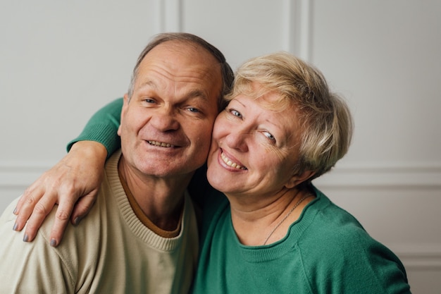 Couple de personnes âgées étreignant et souriant.