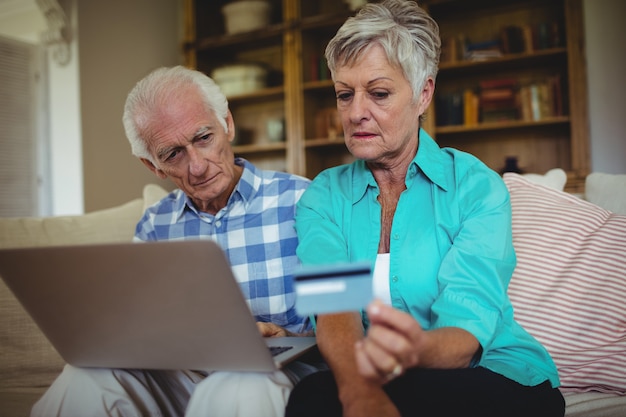 Couple de personnes âgées faisant des achats en ligne sur ordinateur portable