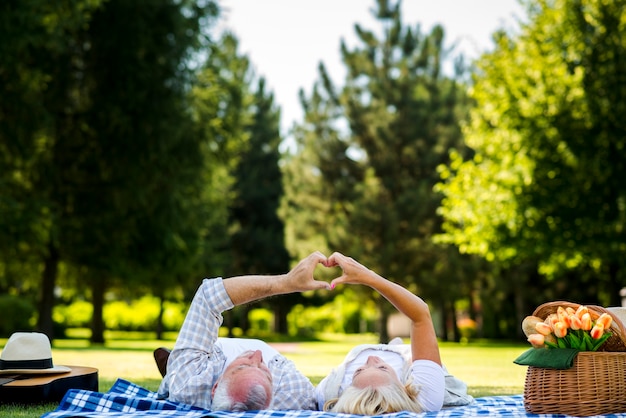 Photo couple de personnes âgées faisant le coeur avec les mains