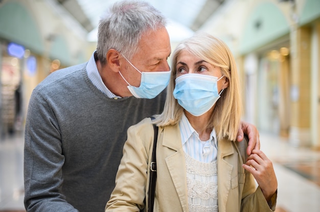 Couple de personnes âgées faisant du shopping dans un centre commercial à l'époque des coronavirus, portant des masques