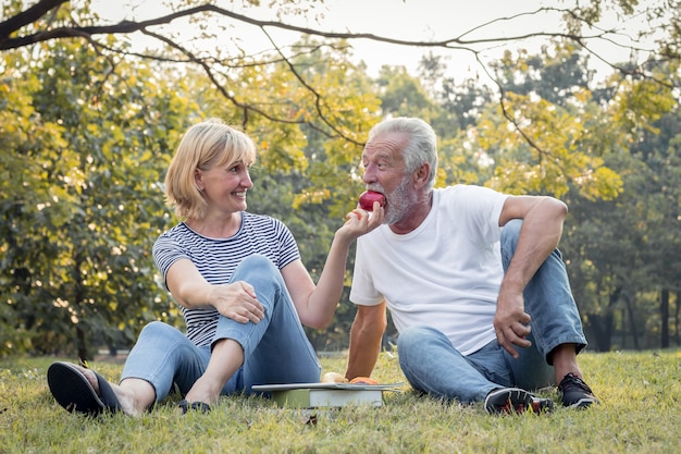 Couple de personnes âgées sur l'herbe dans le parc