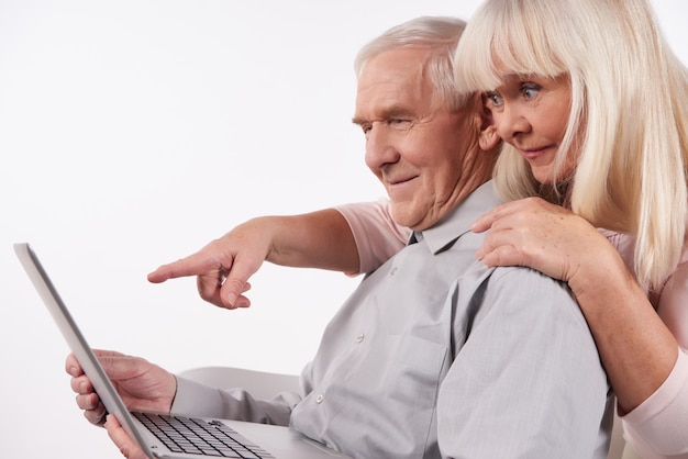 Photo un couple de personnes âgées interagit avec un ordinateur portable.