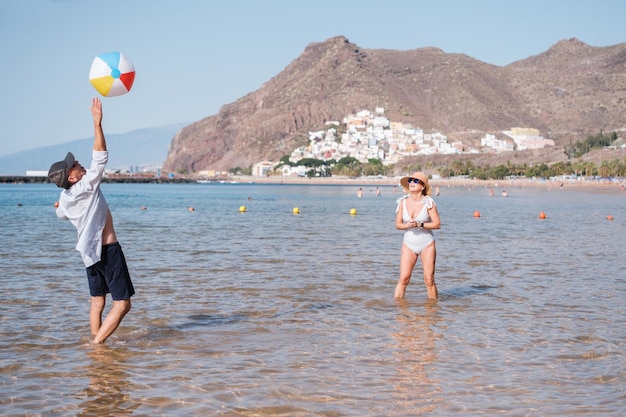 Couple de personnes âgées jouant avec le ballon de plage tout en se rafraîchissant dans la mer Sport de plein air de style de vie Concept