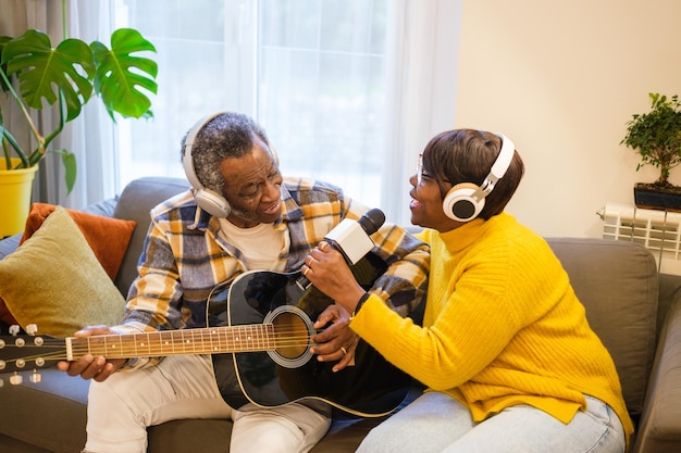 Couple de personnes âgées jouant de la guitare et chantant ensemble dans leur salon en profitant de leur temps libre Concept retraite musique divertissement