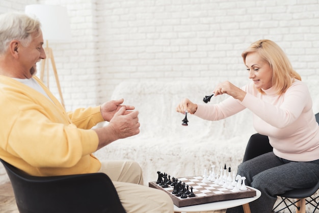 Un couple de personnes âgées joue aux échecs à la maison.