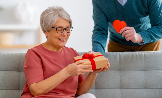 Couple de personnes âgées le jour de la saint-valentin Joyeuse belle femme âgée souriante tout en recevant un cadeau