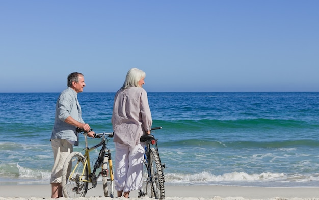 Couple de personnes âgées avec leurs vélos sur la plage