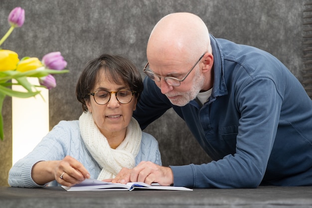 Photo couple de personnes âgées lisant un livre à la maison