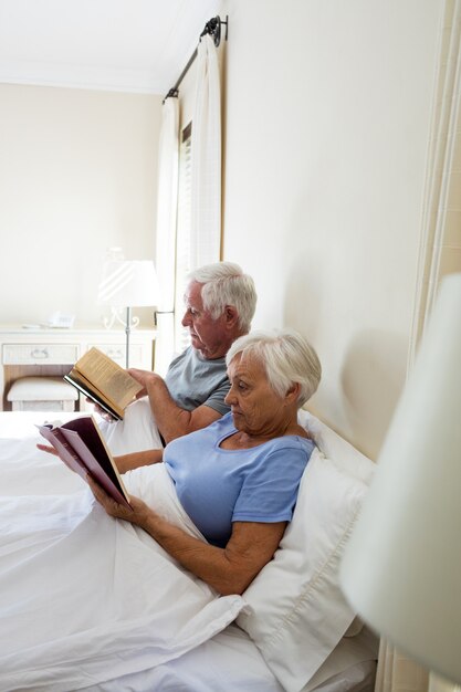 Couple De Personnes âgées Lisant Des Livres Dans La Chambre à La Maison