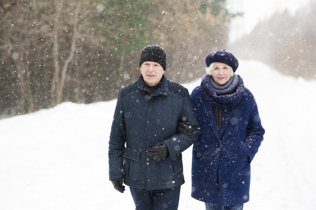 Couple de personnes âgées marchant à l'extérieur en hiver